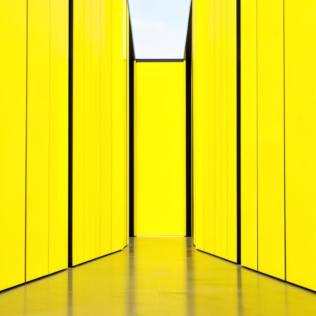 Clean architectural photograph with strong symmetry, a modern glass building facade reflecting soft morning light